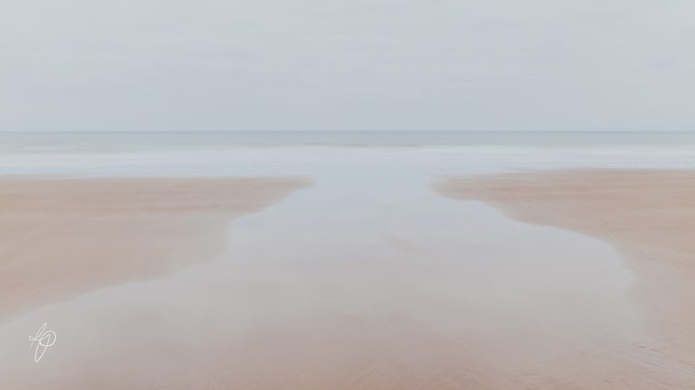 A peaceful seascape of sand, sea and water.